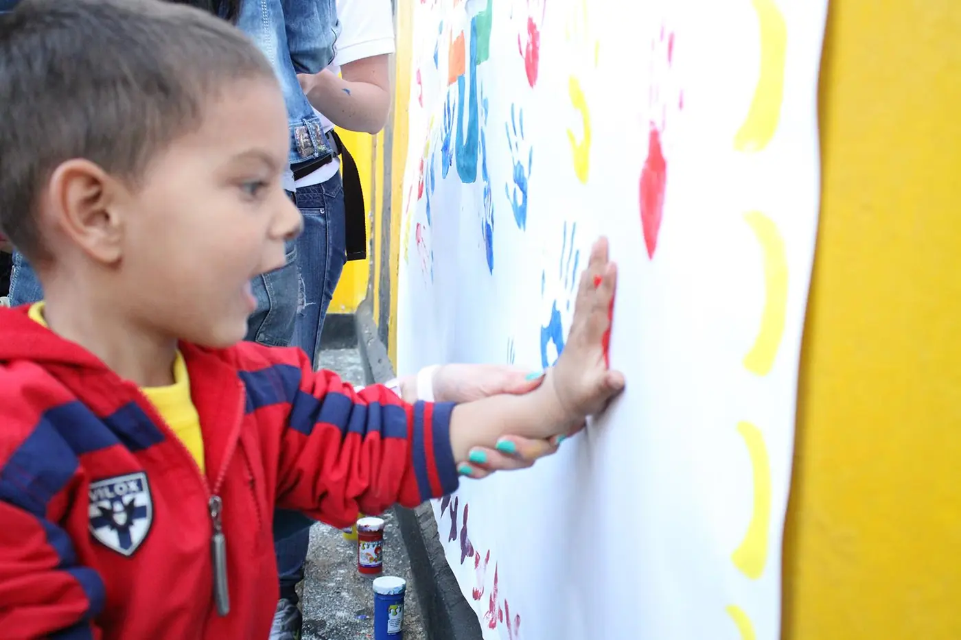 Niño dejando su mano pintada sobre el mural